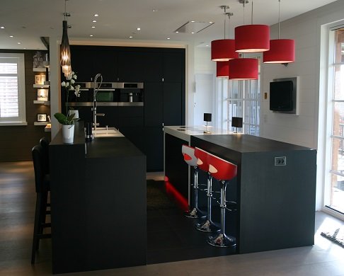 Cuisine ouverte en chêne teinté noir avec bar, tabourets rouges et suspensions